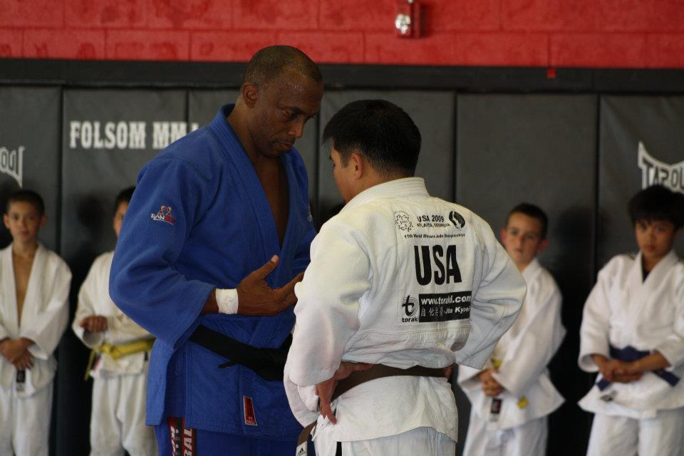 Coach David Butler giving one-on-one instruction to a young judoka in a USA judogi